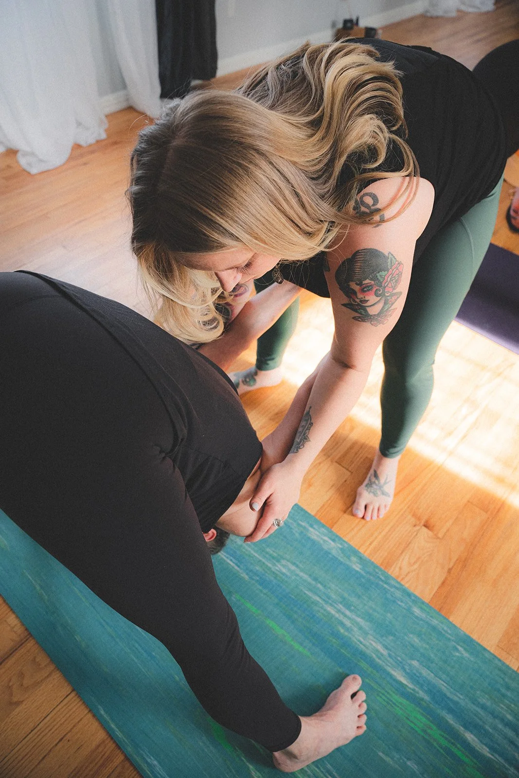 Lauren Reek private yoga teacher Long Island hands on adjustment with student in ashtanga yoga pose, wide legged forward fold