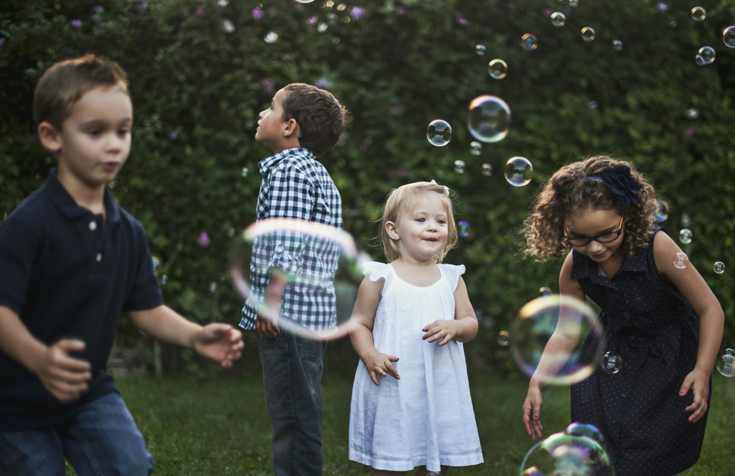 Four kids playing outside with bubbles