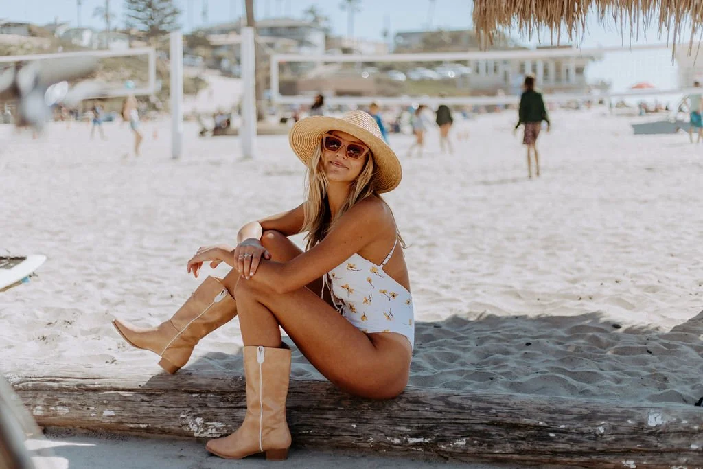 San Diego woman in a straw hat sitting in the shade at the beach