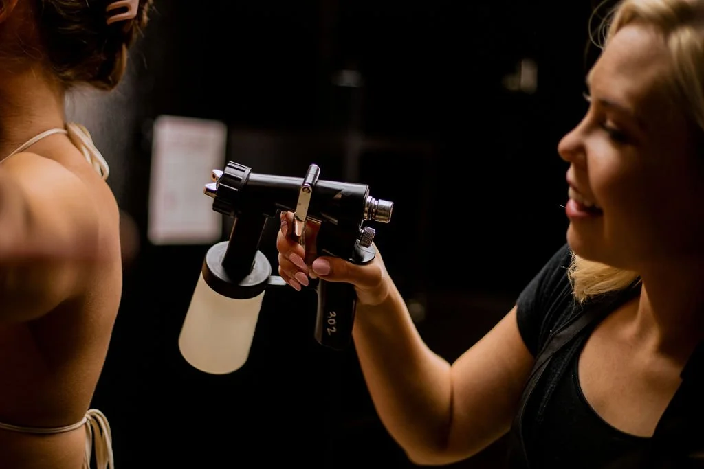 San Diego spray tan technician spraying custom tanning solution on client