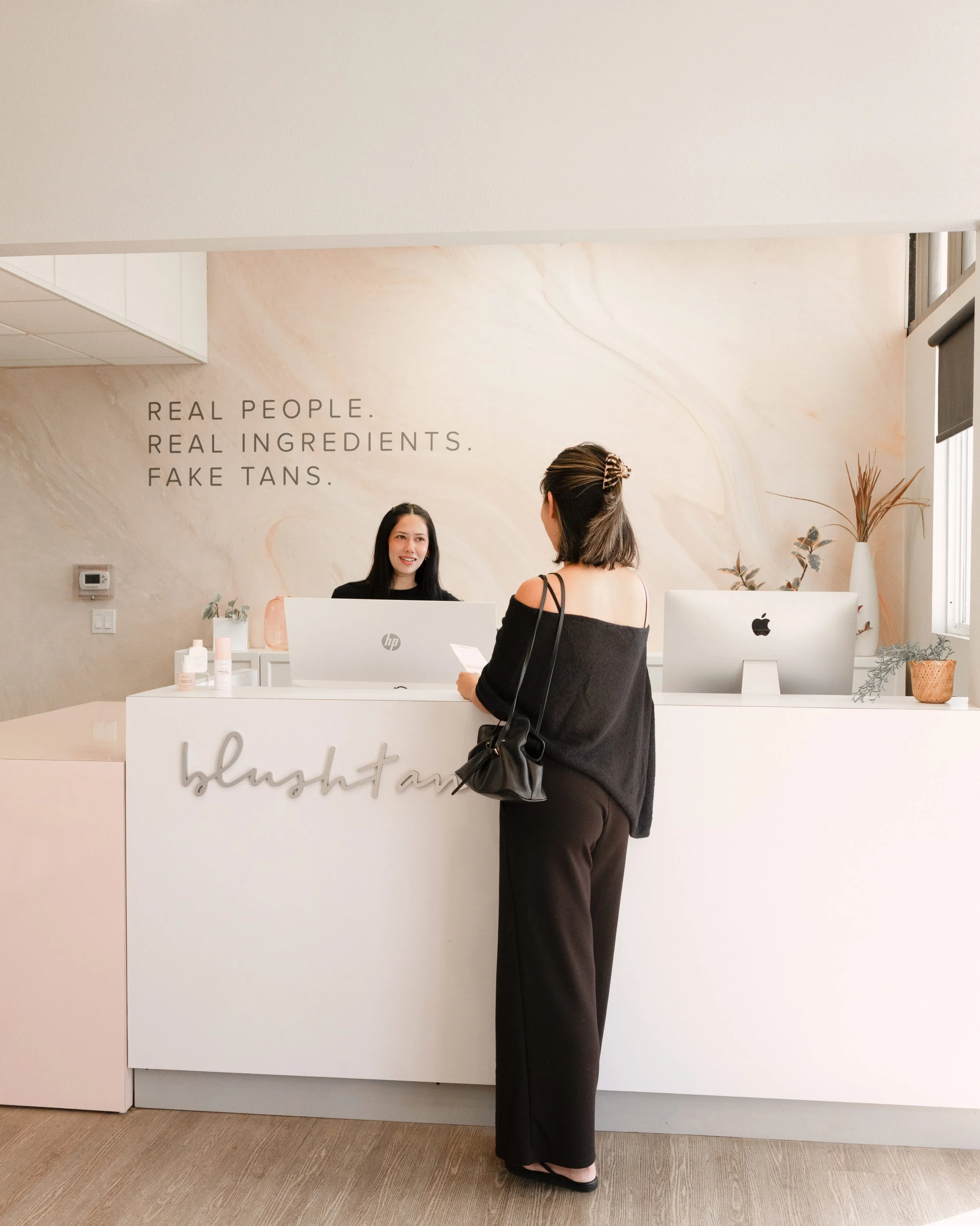 interior photo of BlushTan San Diego, woman behind the counter helping customer