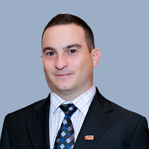 Professional portrait of a man in a suit and tie against a light blue background.