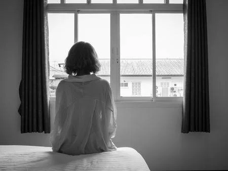 106546980-woman-short-hair-sitting-on-the-white-bed-in-hotel-room-lonely-woman-looking-out-the-window-alone-in.jpg