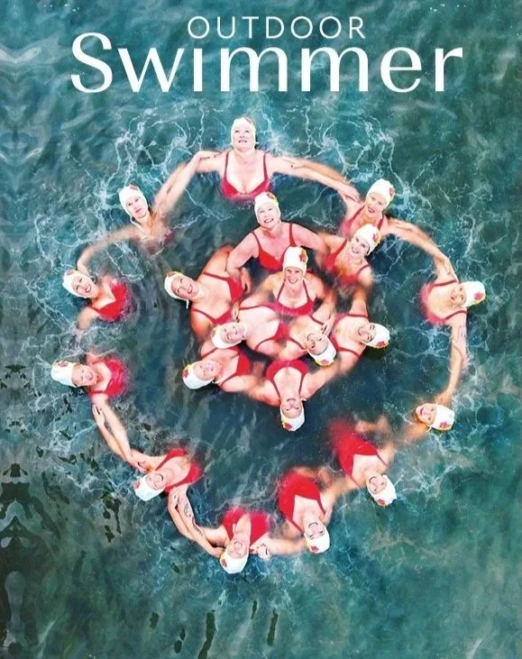 Outdoor Swimmer magazine cover: aerial view of synchronised swimmers in red costumes forming a circular flower formation