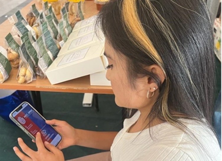 Young woman from Kyrgyzstan, seen from the side, looking at the screen of a smartphone