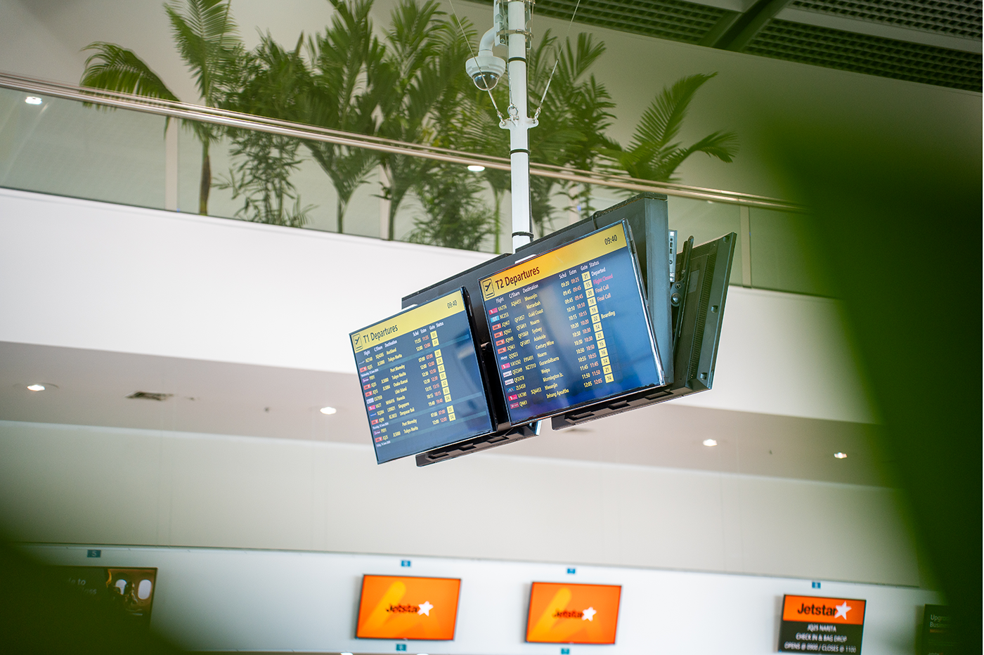 Cairns International T1 Airport. Airport departure screens displaying flight information with tropical plants in the background. Airport Interior Design Brisbane Australia