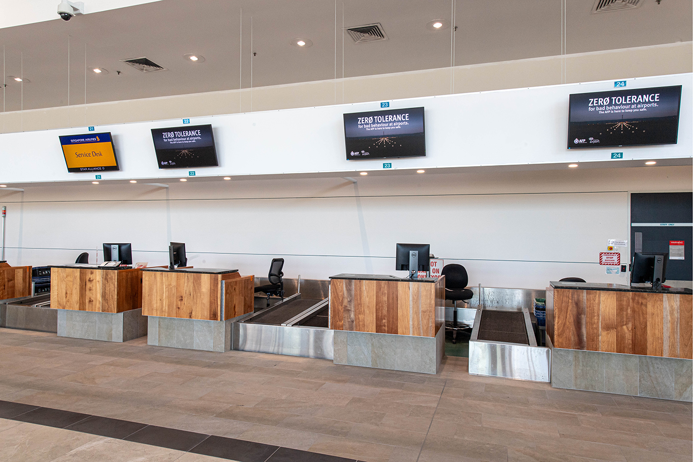 Cairns International T1 Airport. Empty airport check-in counters with computer monitors and signage. Airport Interior Design Brisbane Australia