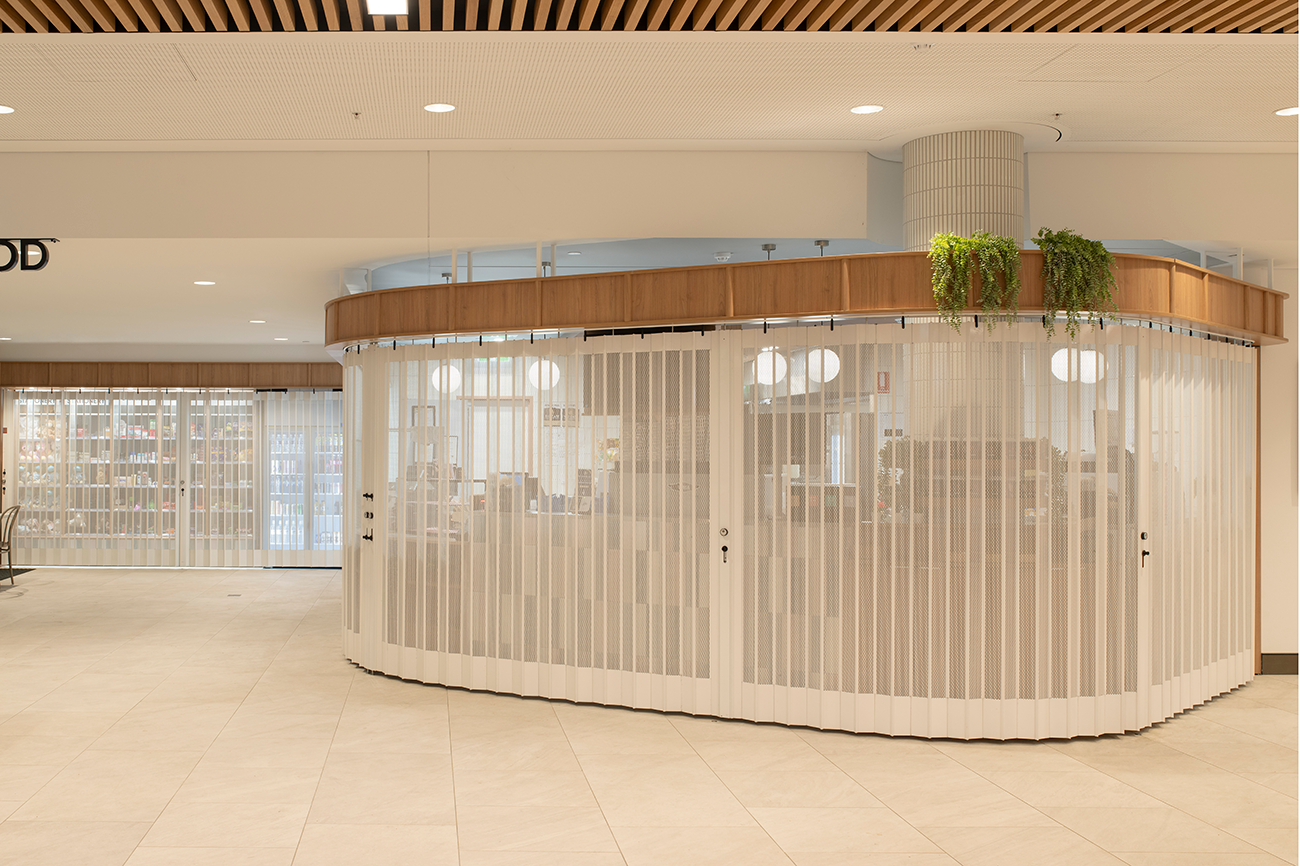 Prince Charles Hospital Foundation Common Good Cafe. Indoor cafe with white mesh folding doors, wooden accents, and potted plants on top. Food and beverage Interior Design Brisbane Australia