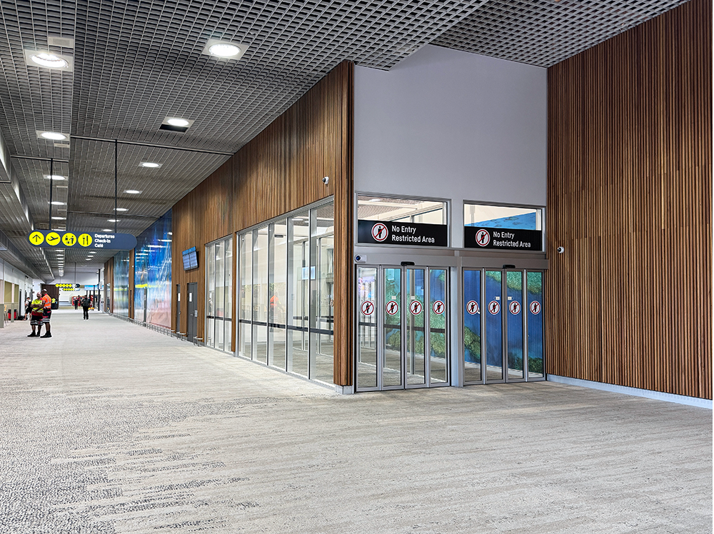 Airport corridor with wood paneling, restricted area doors, and overhead directional signs.
Townsville Airport. Interior Design Australia