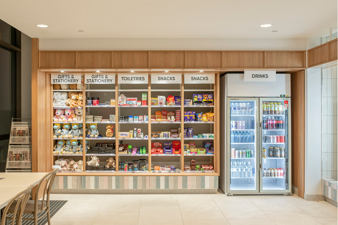 Prince Charles Hospital Foundation Common Good Cafe. A convenience store display with shelves labeled gifts, stationery, toiletries, snacks, and drinks. Food and beverage Interior Design Brisbane Australia