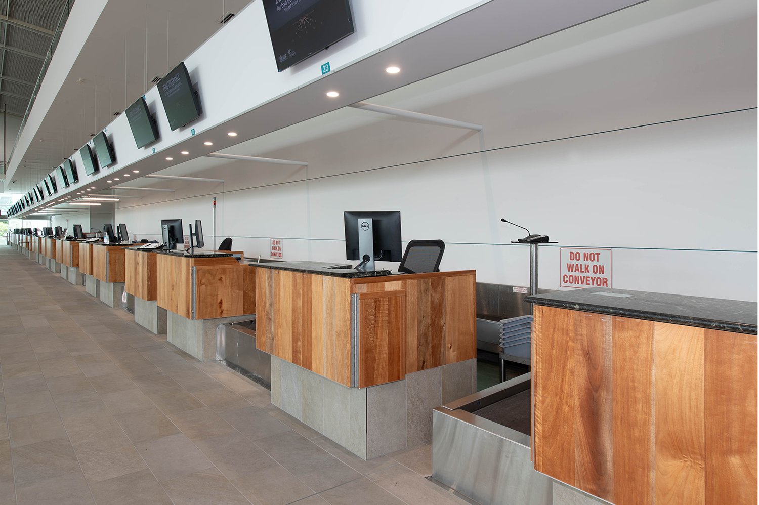Cairns International T1 Airport. Empty airport check-in counters with monitors and wooden desks. Airport Interior Design Brisbane Australia