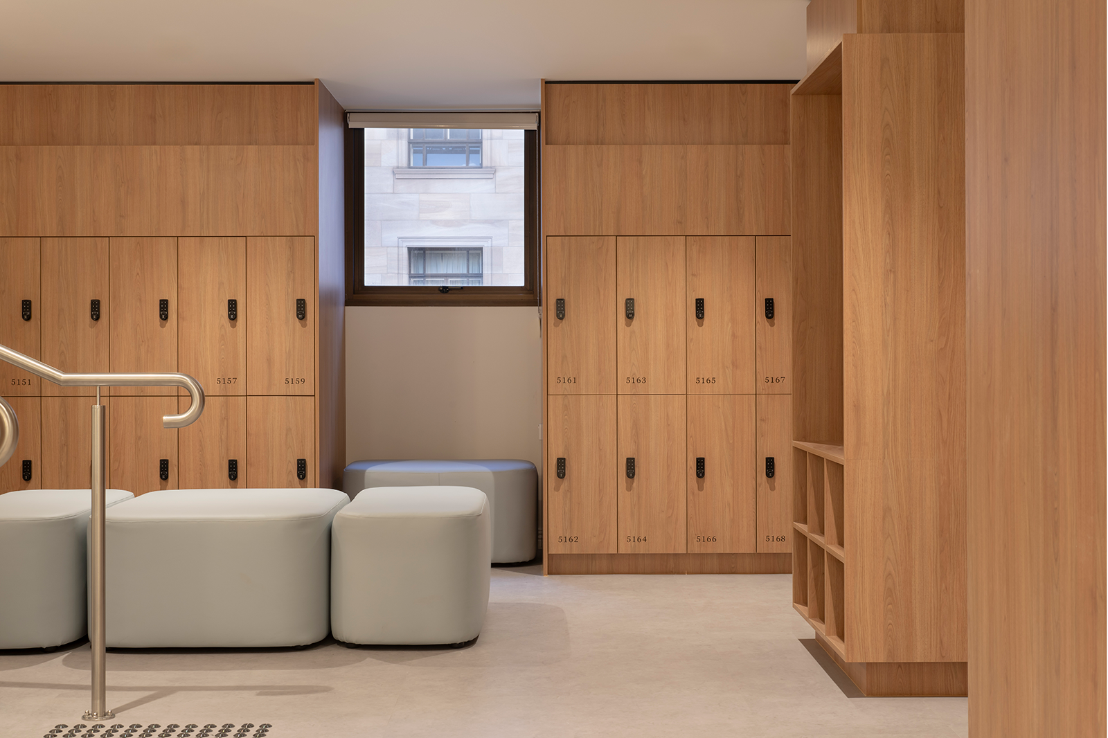 Tattersall's Club. Wooden lockers with black handles, light blue seating, and a window with a view of a building exterior. Hospitality Interior Design Brisbane Australia