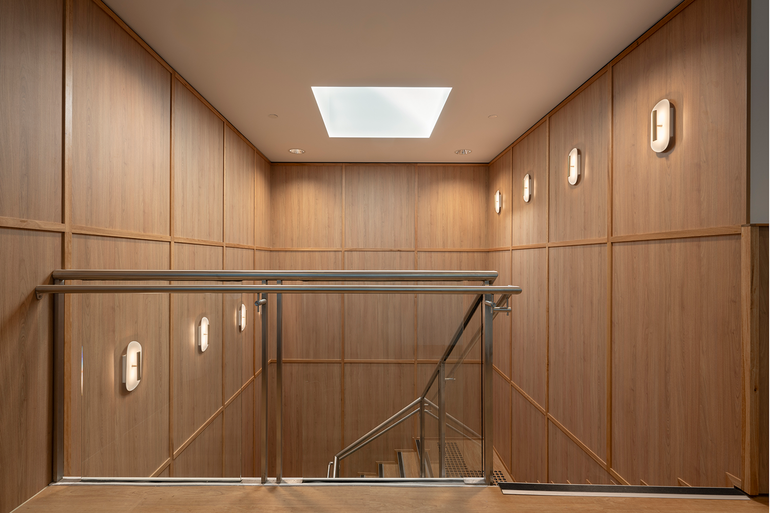 Tattersall's Club. Modern staircase with wooden walls and stainless steel railings, featuring wall-mounted lights and a square ceiling light. Hospitality Interior Design Brisbane Australia