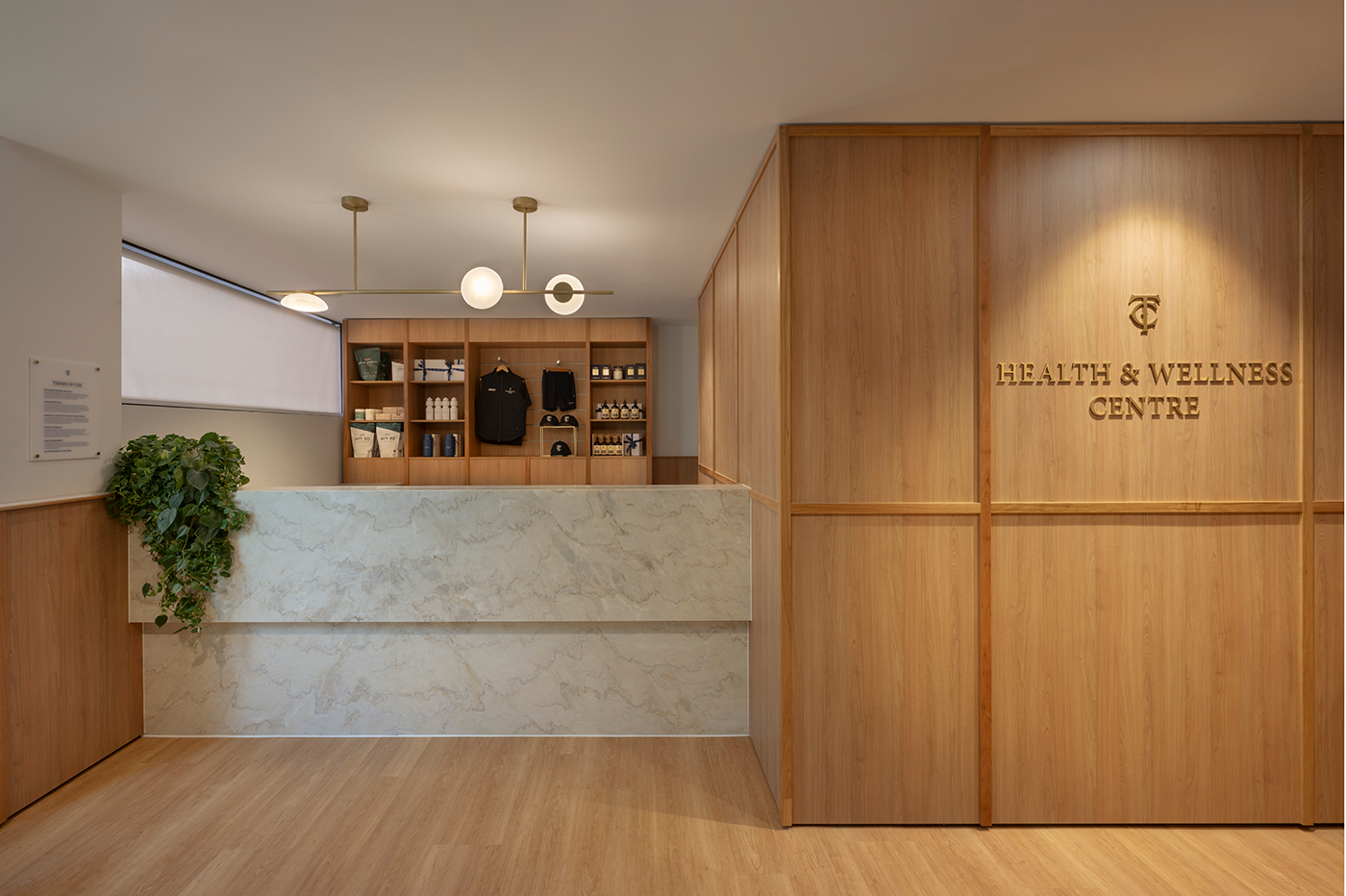 Reception area of a health and wellness center with wooden panels, shelves displaying merchandise, and a light marble counter. Tattersall's Club. Hospitality Hotel Restaurant Interior Design Brisbane Australia