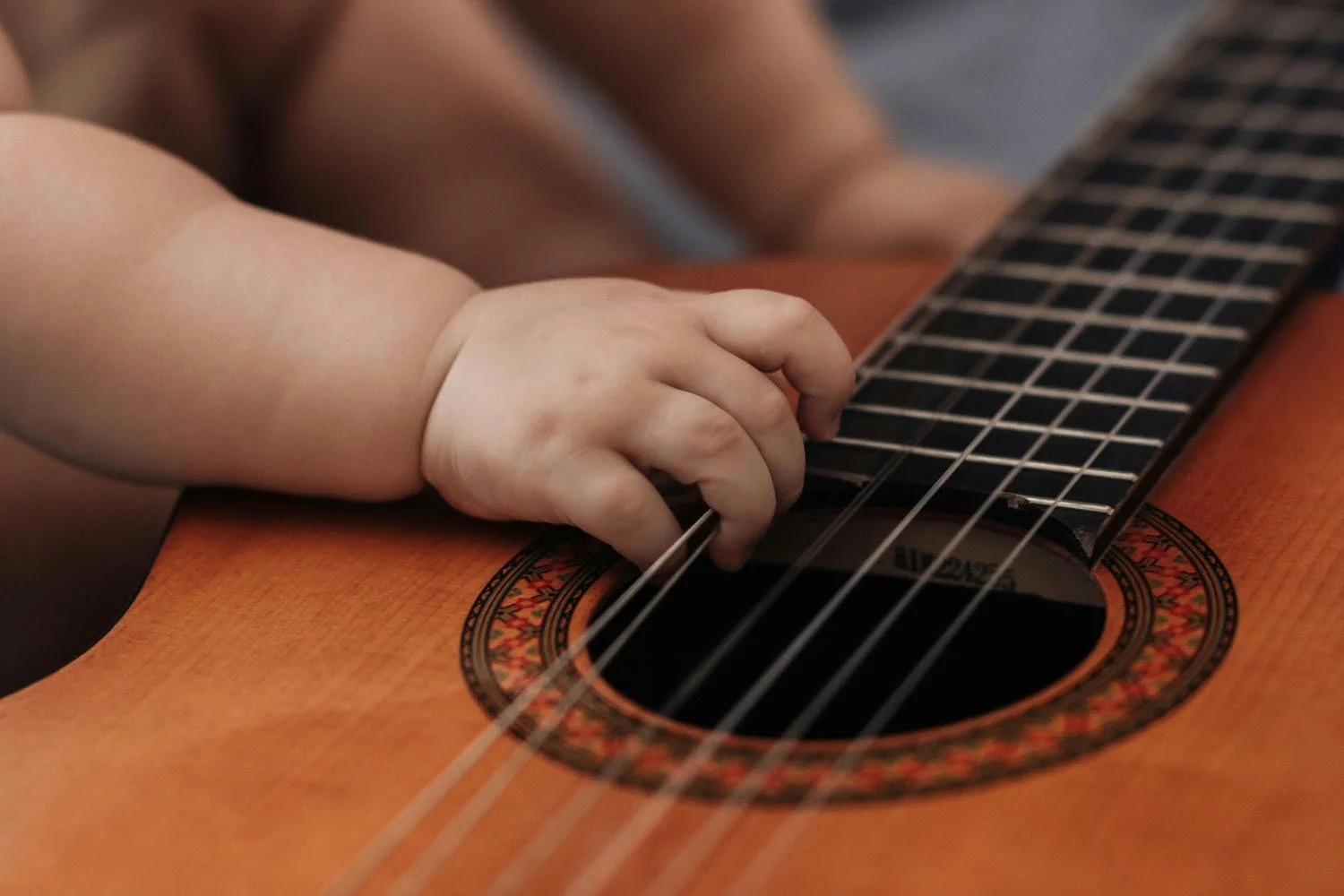 Chubby baby fingers playing guitar strings