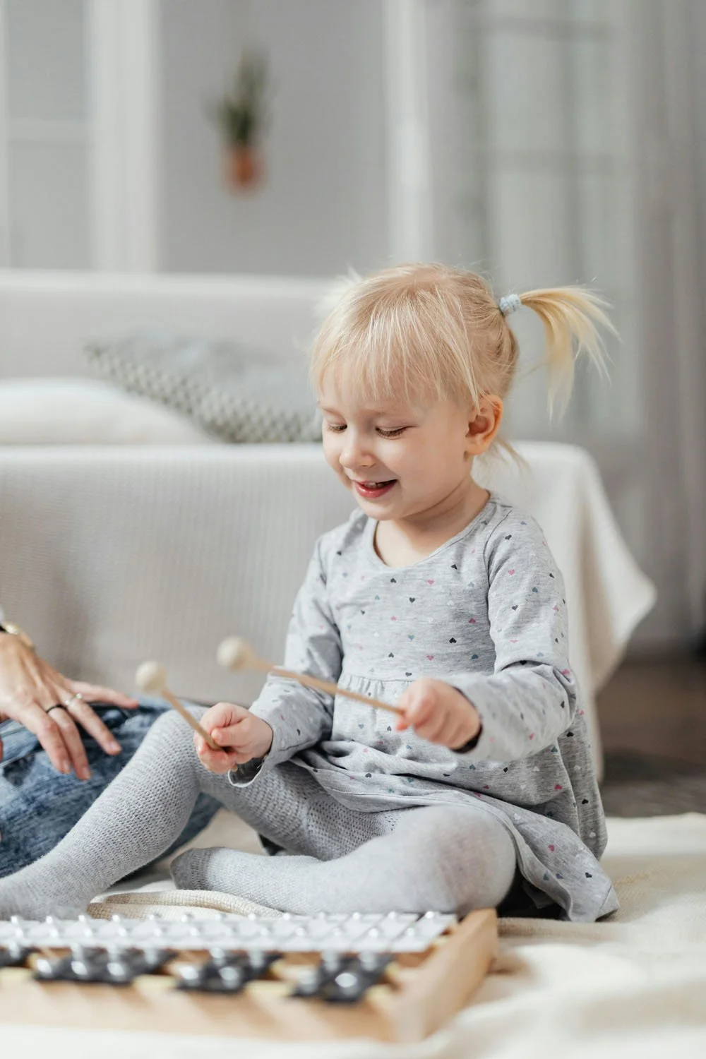 Toddler with xylophone beaters in her hands smiles at a portland baby music class