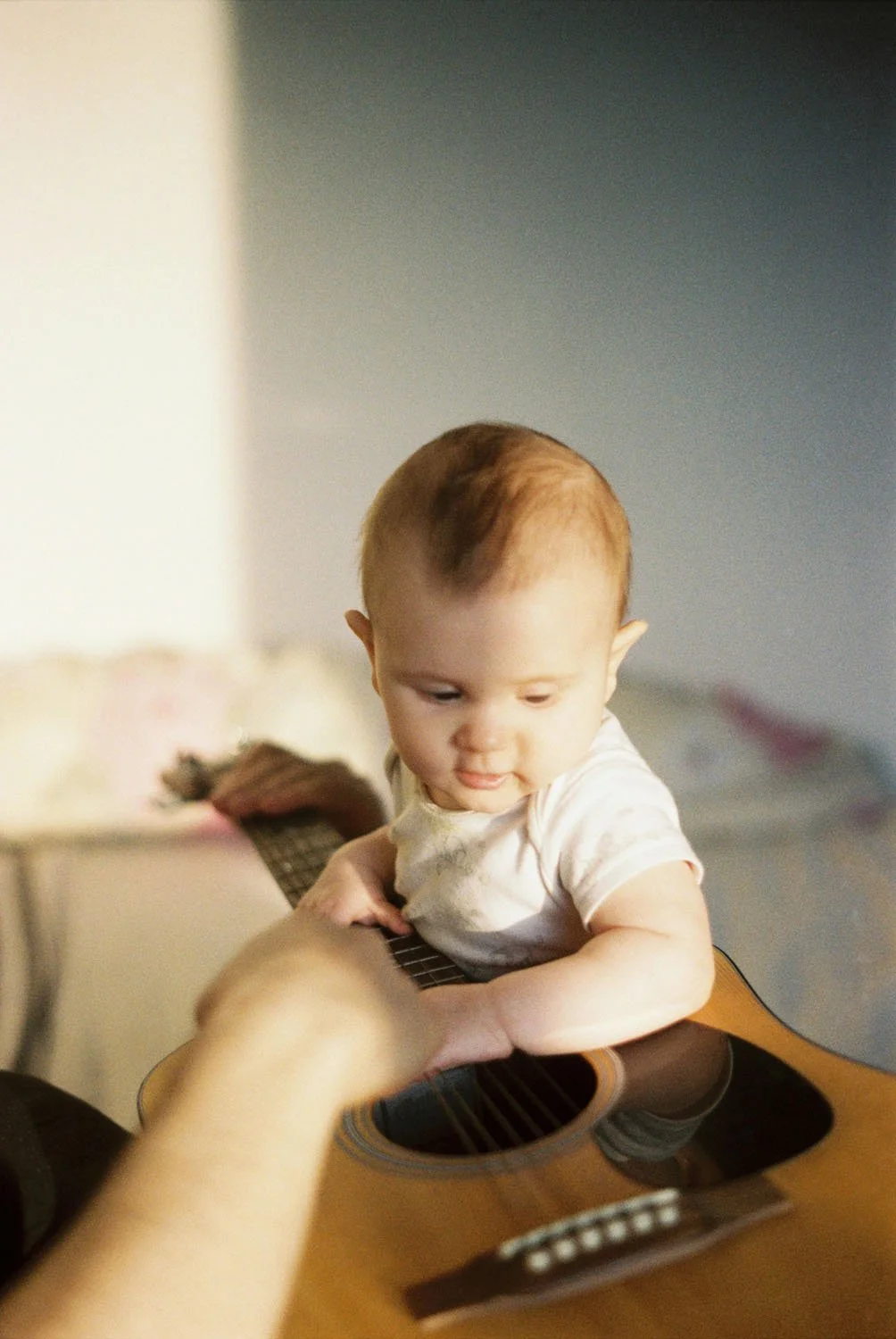 Curious baby looks at and touches guitar