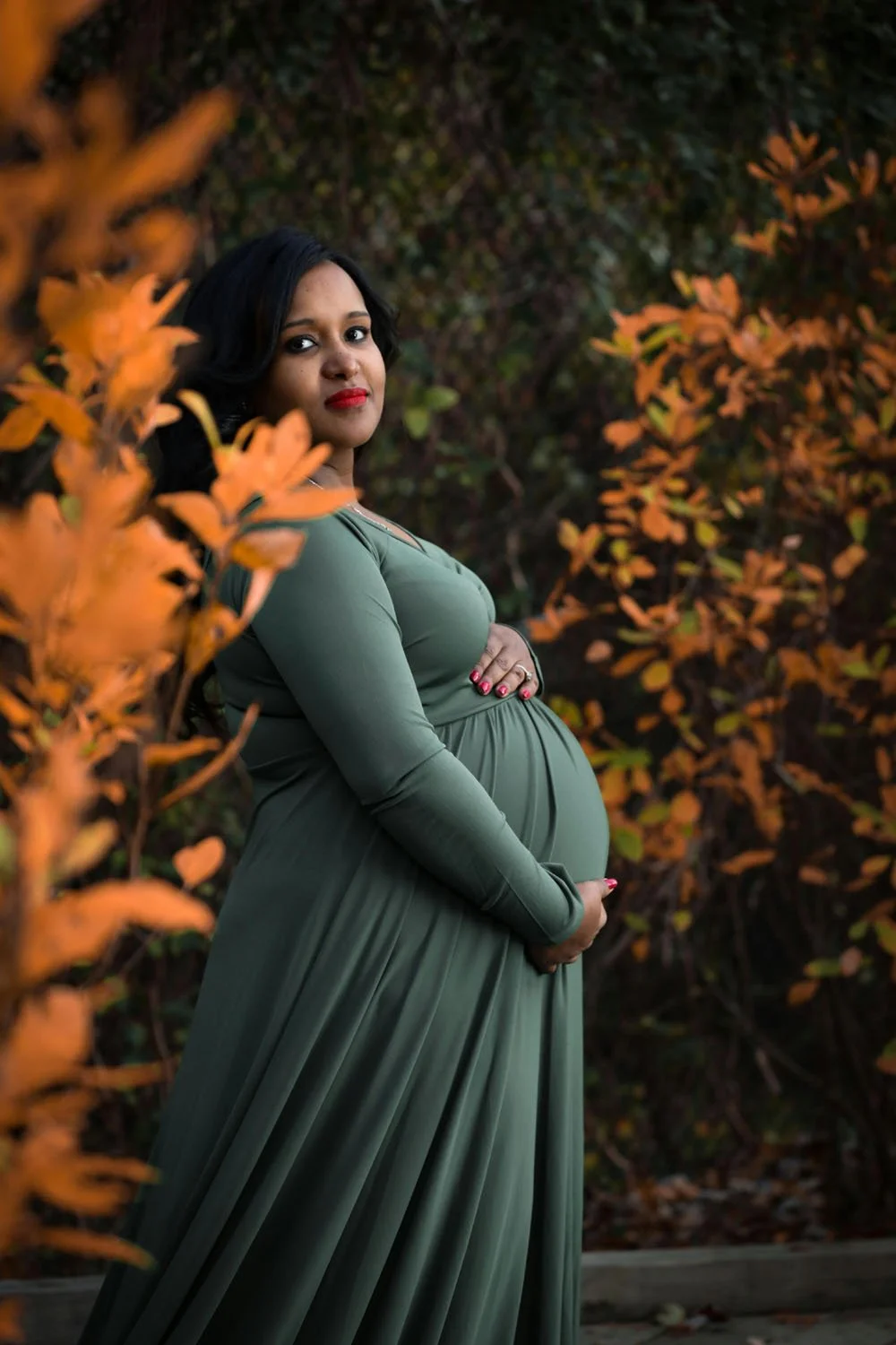Portland pregnant mother poses in leafy garden showing baby bump