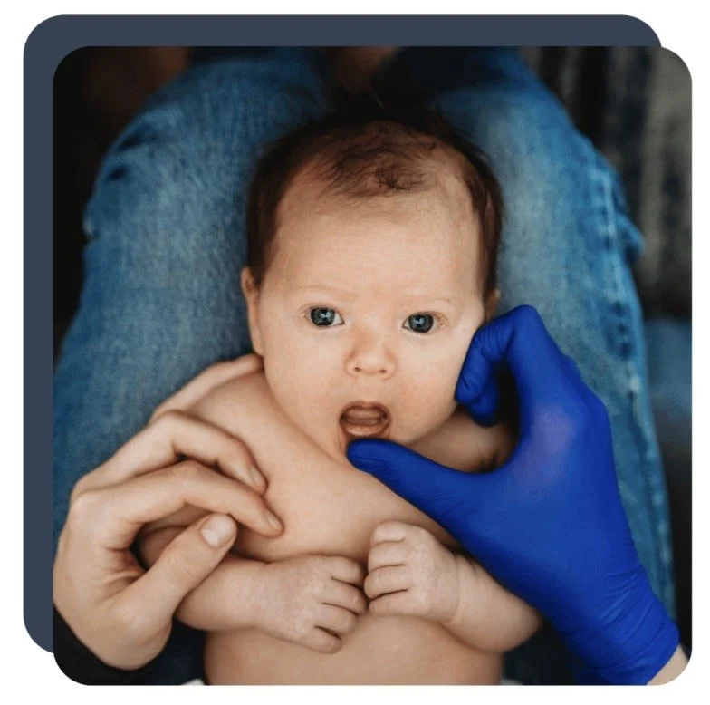 Gloved hand of lactation consultant portland opening newborn baby's mouth