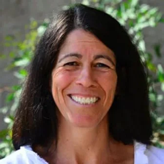 Close-up of a woman with shoulder-length dark hair smiling outdoors