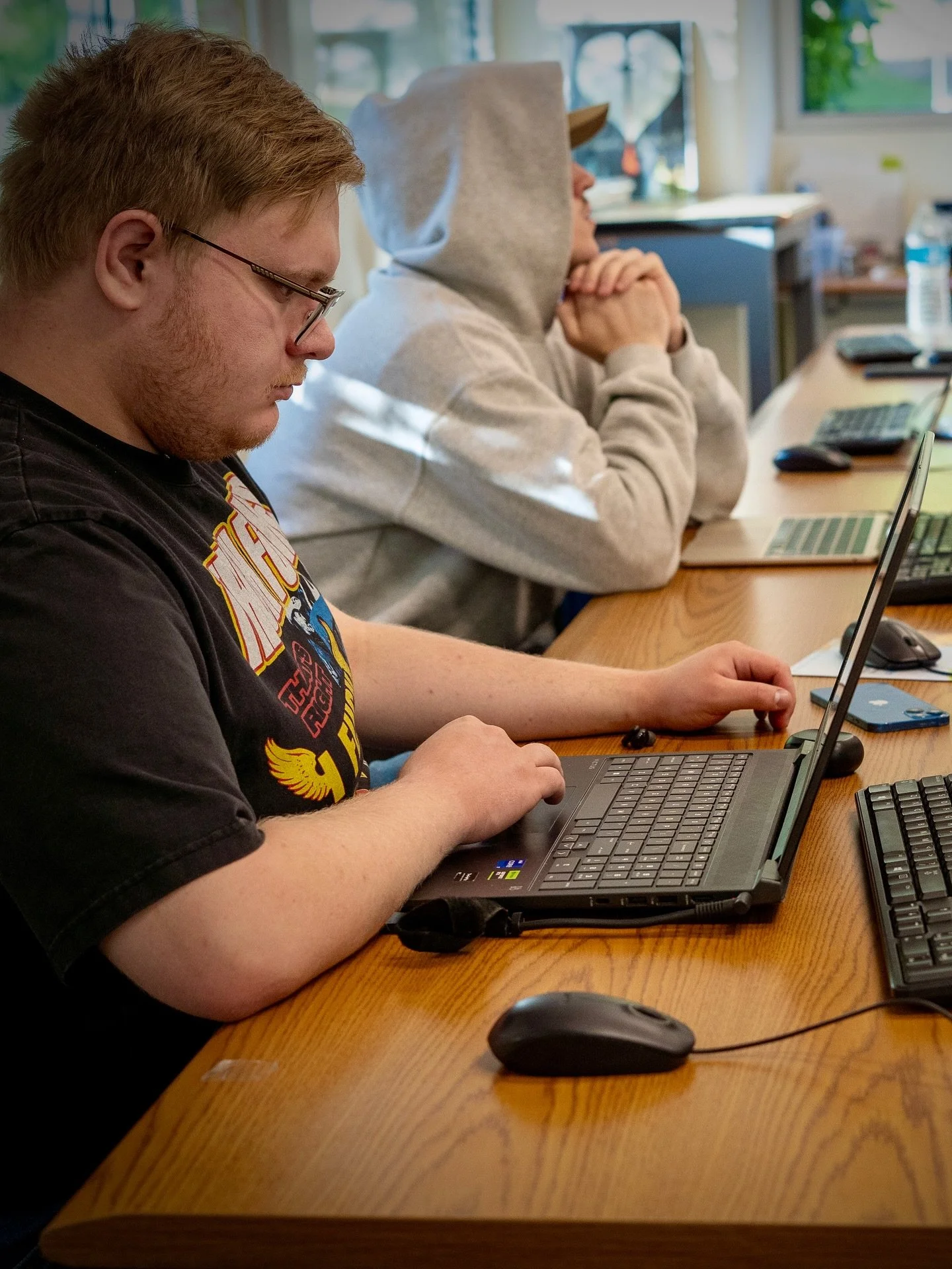 A person with a beard wearing headphones working on a laptop in a dimly lit room.