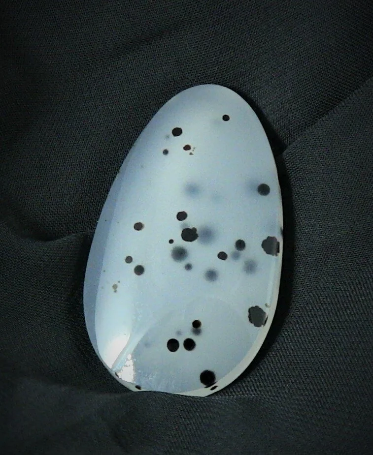 An empty white ceramic spoon resting on a dark fabric surface.