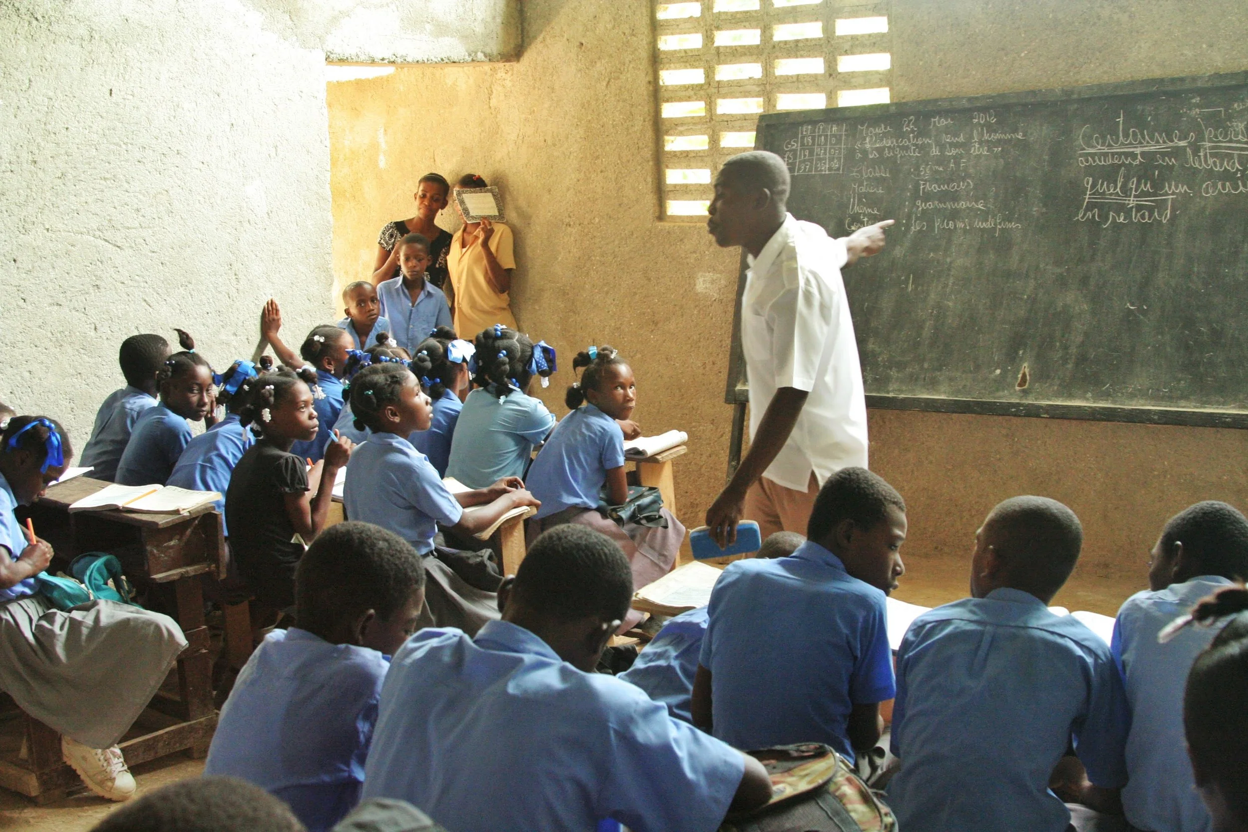 Male teacher in front of his class, pointing to a chalkboard
