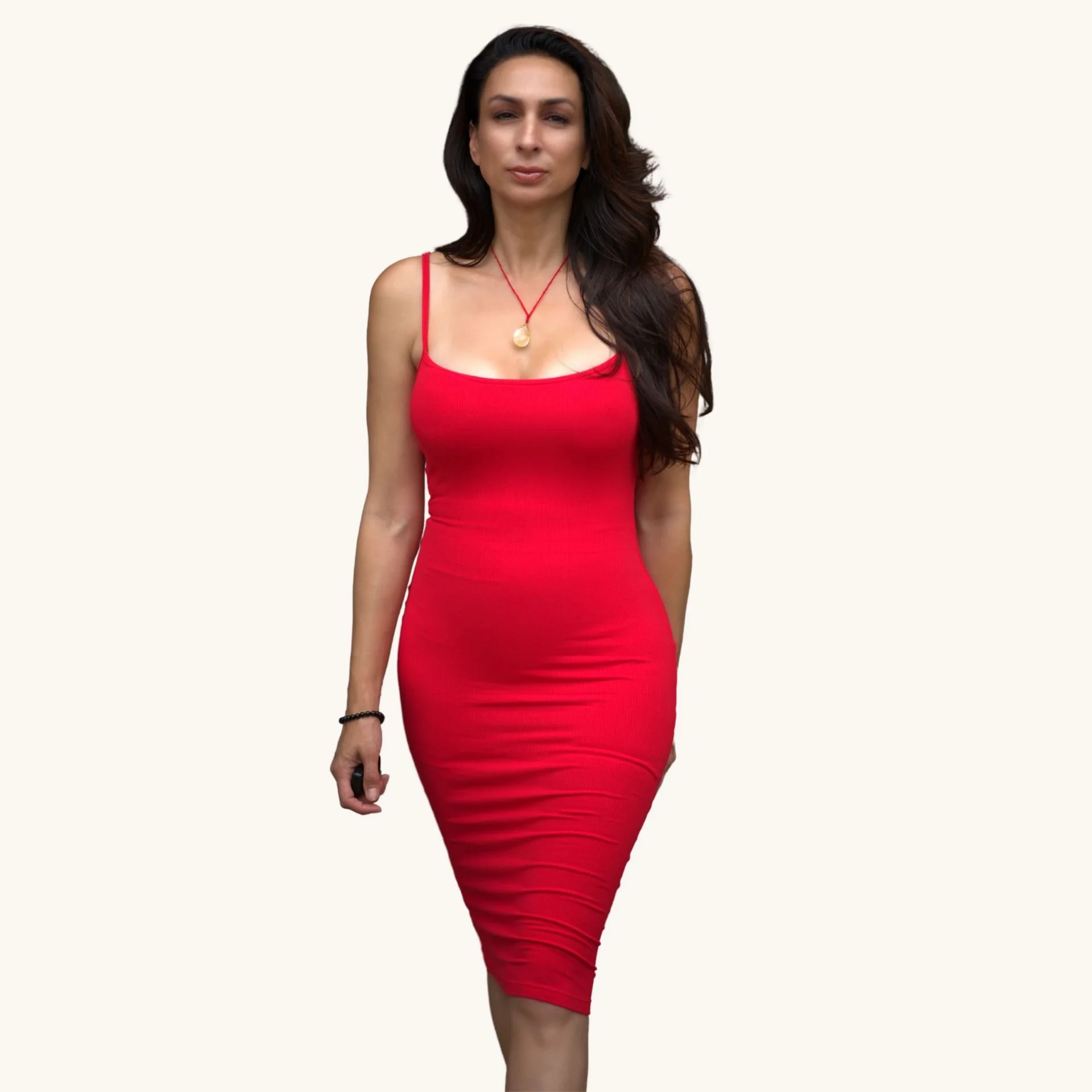 Woman in a red dress with long dark hair, standing against a plain light background.