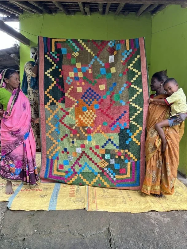 Two-quilters-from-Baichwada-hold-up-a-quilt-that-they-worked-together-on.-610x813.jpeg