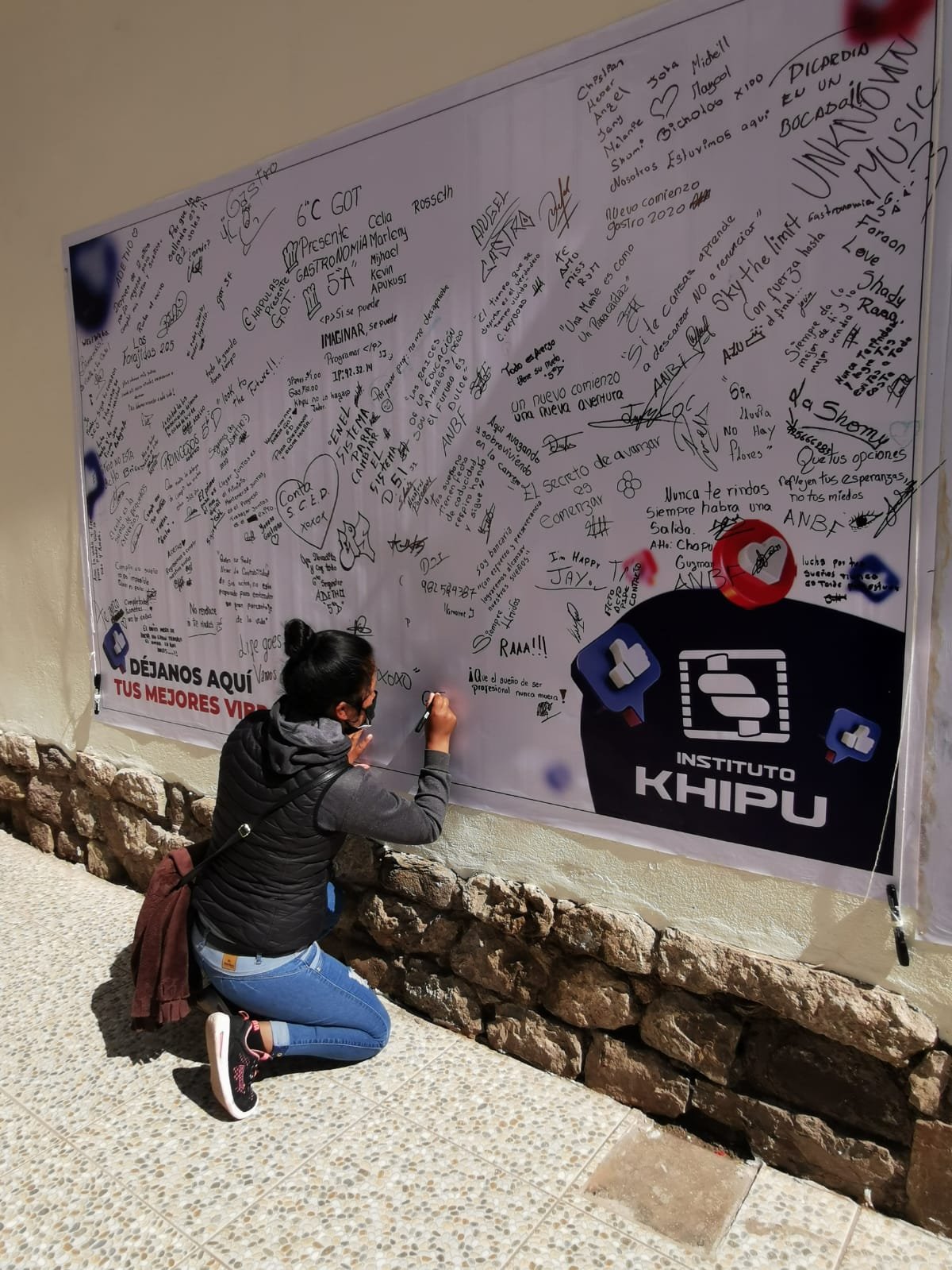 Cleyde adds her own inspiring messages to those of her fellow students, as she signs the "good wishes" poster at the Khipu Institute.