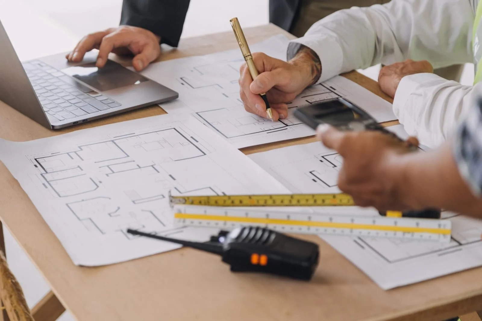 Two professionals reviewing a shopping center site plan and trade area map at a conference table