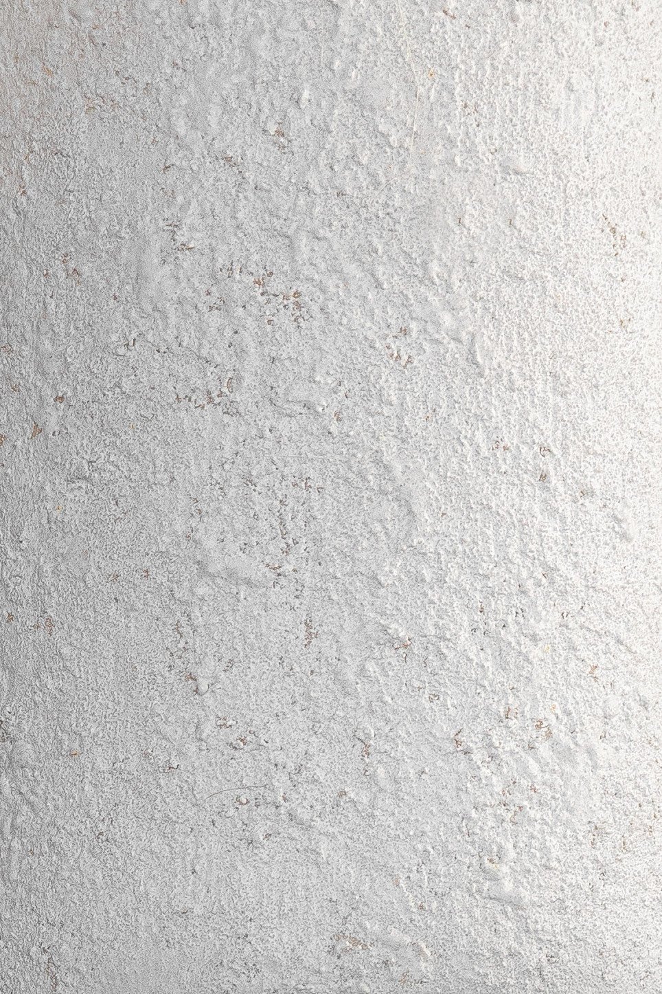 Close-up of a lamp's cylindrical shade with a textured stone effect. Gray tone variations and intricate natural indentations create an organic and elegant appearance.