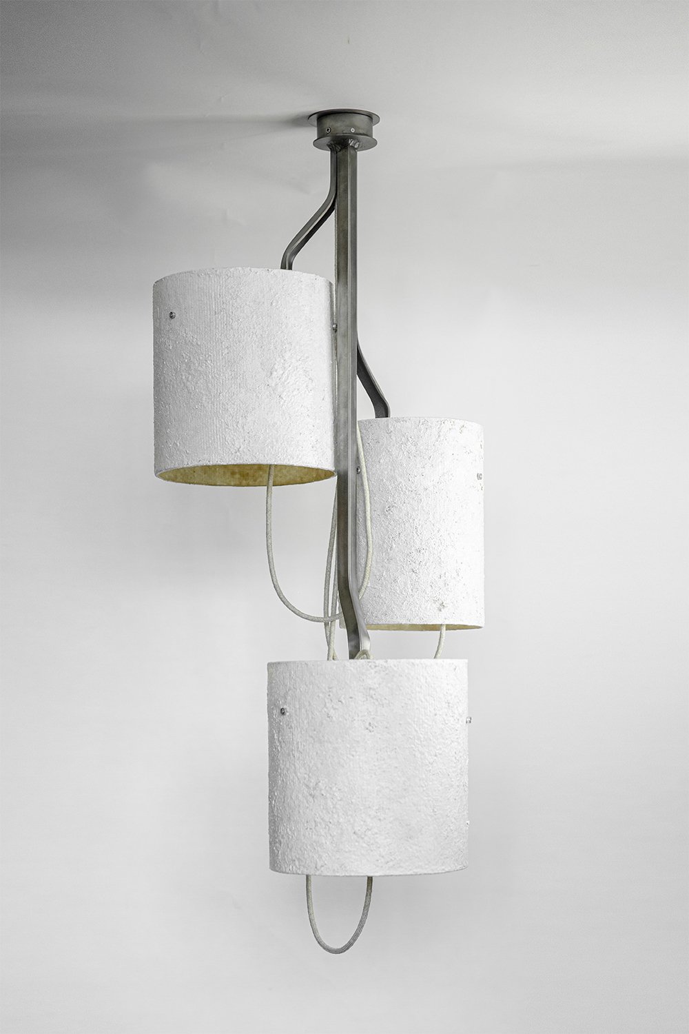 Ceiling-mounted light with three white stone-effect shades on curved metallic arms extending from a central frame. Mounted on a circular ceiling rose, it blends minimalism with artistry.