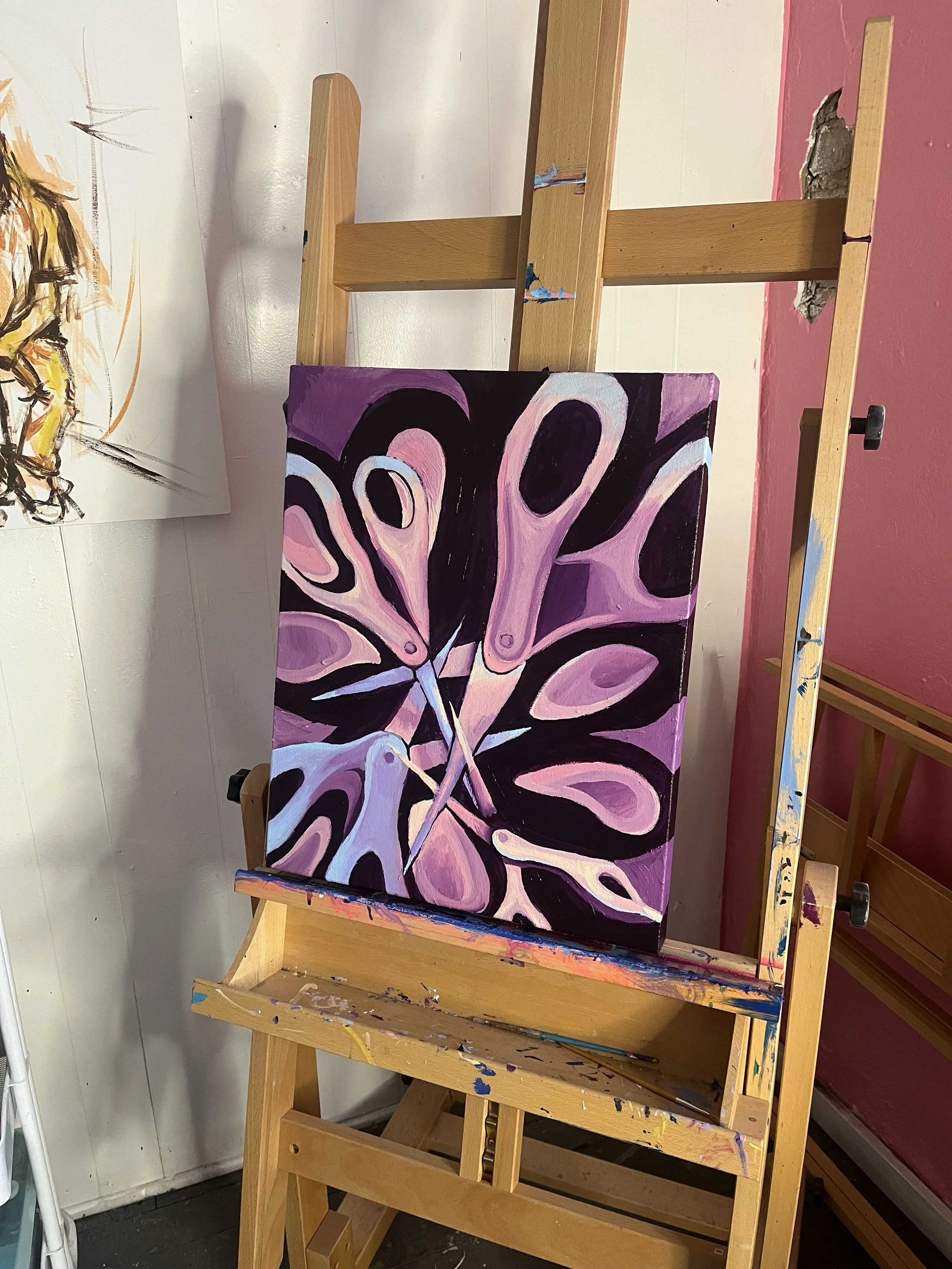 Abstract painting on canvas featuring pink, purple, and black shapes on an easel in an art studio.