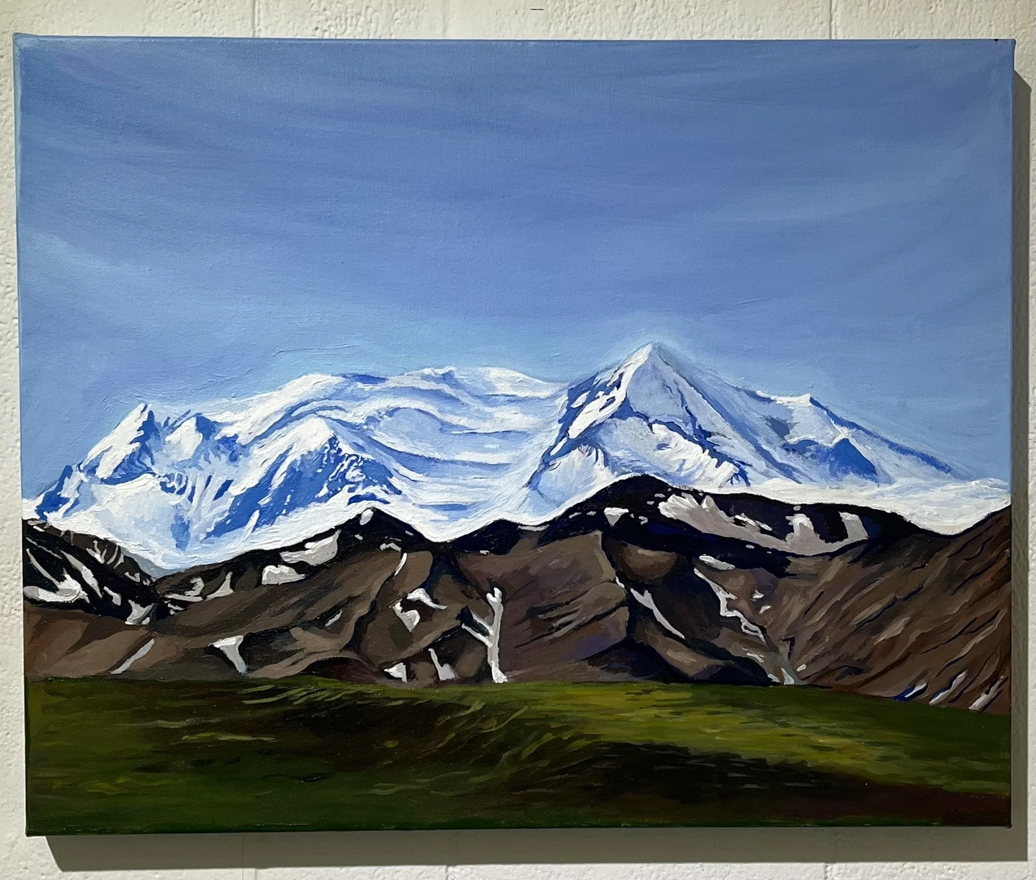 A painting of snow-capped mountains with a grassy green field in the foreground.