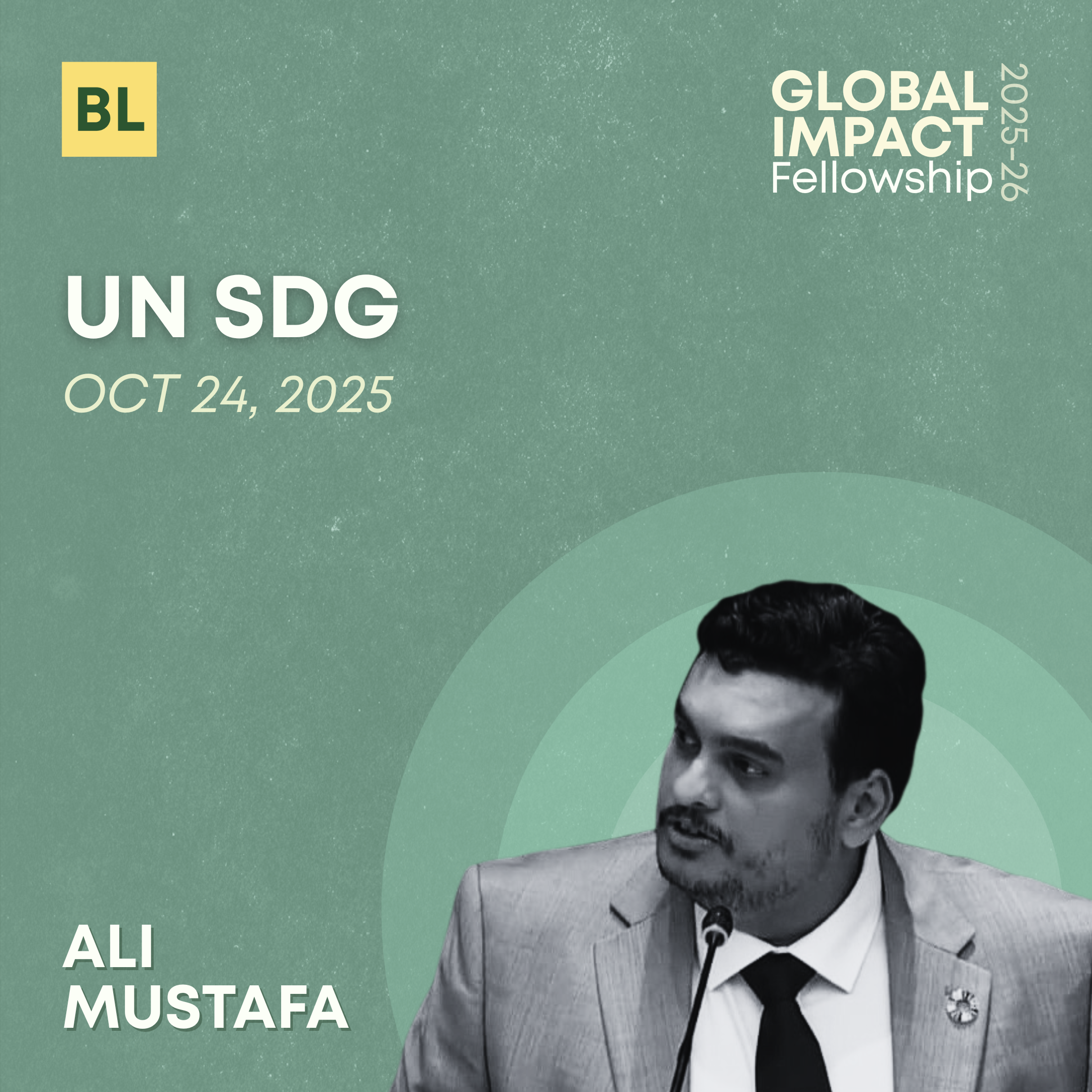 Black and white photo of Ali Mustafa in a suit, speaking at a conference with a microphone.