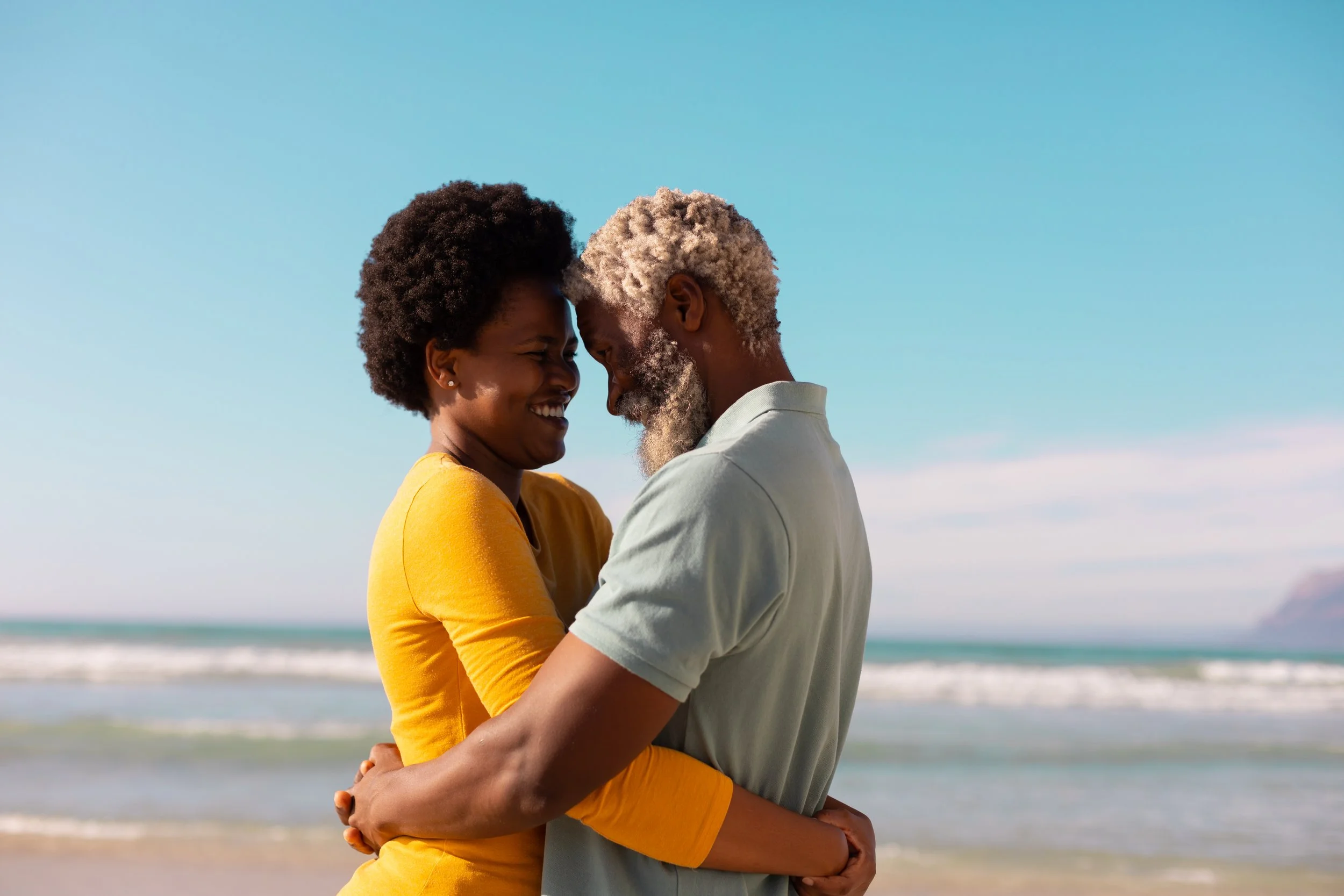 A retired couple embracing on the beach, enjoying financial peace of mind through stable annuity income that supports their lifestyle in retirement.