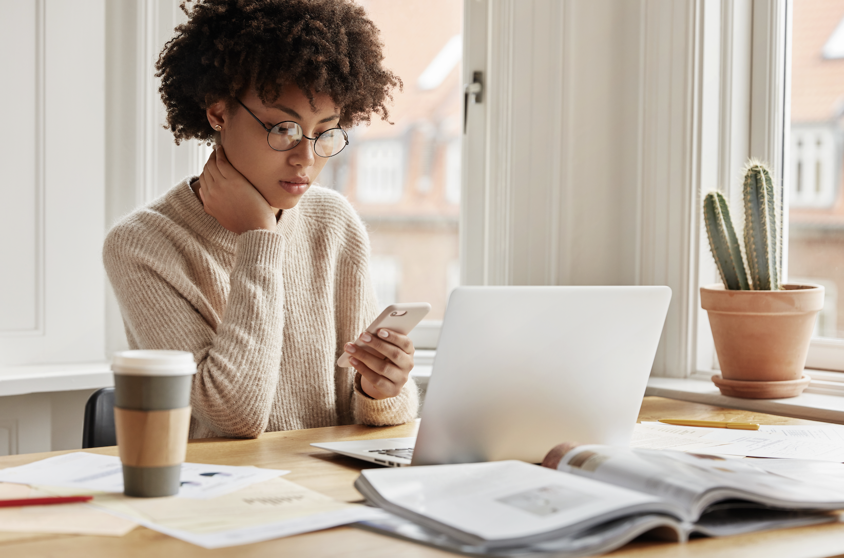 A woman studying at a desk with coffee and books — representing individuals researching insurance policies and coverage options.