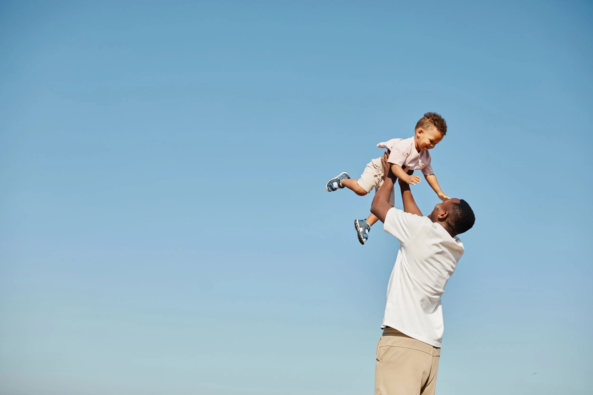 A parent lifting a baby — representing young families protecting their financial future with life insurance.