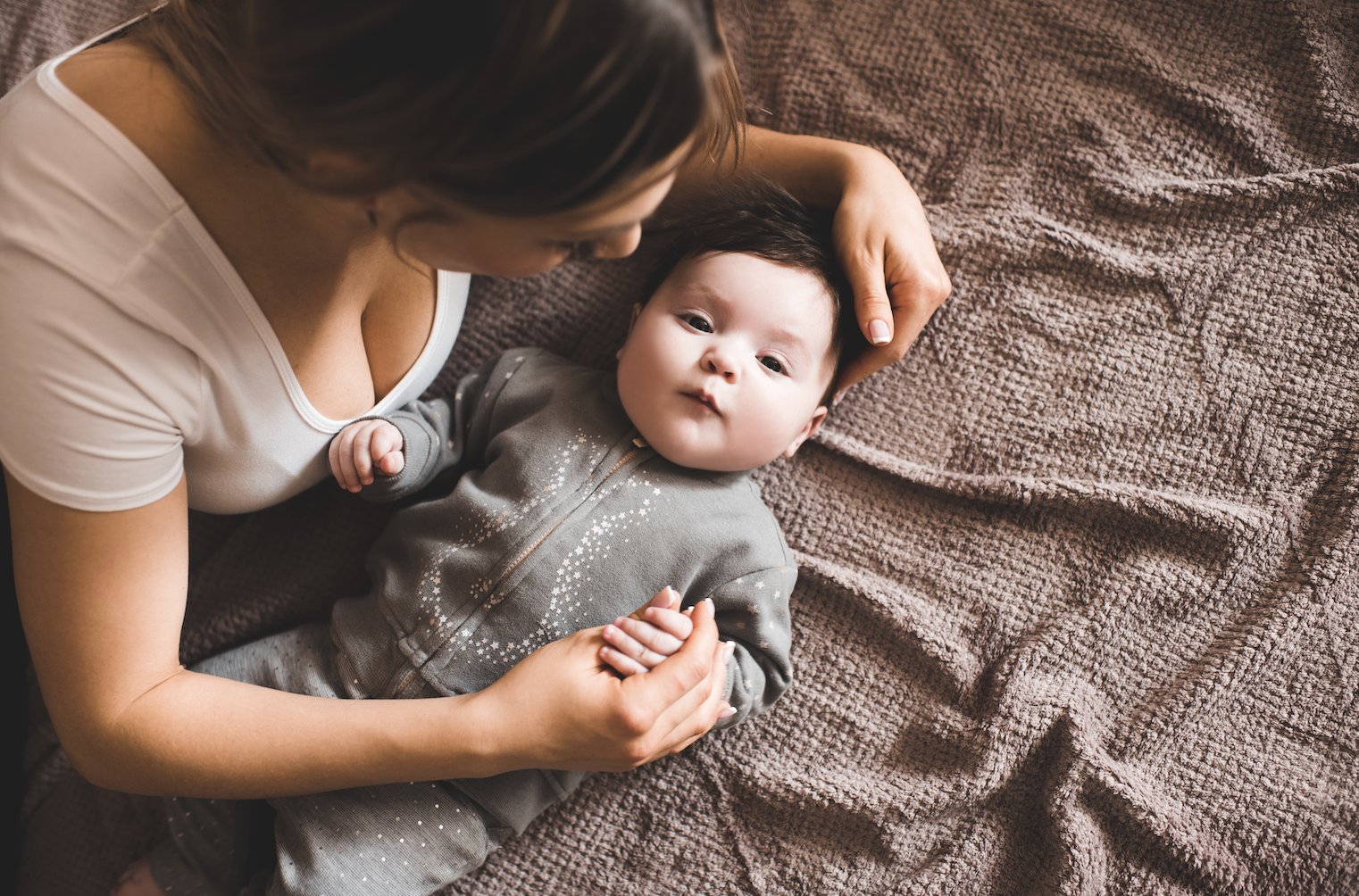 A mother and daughter smiling on a bed — representing family life insurance for long-term stability.