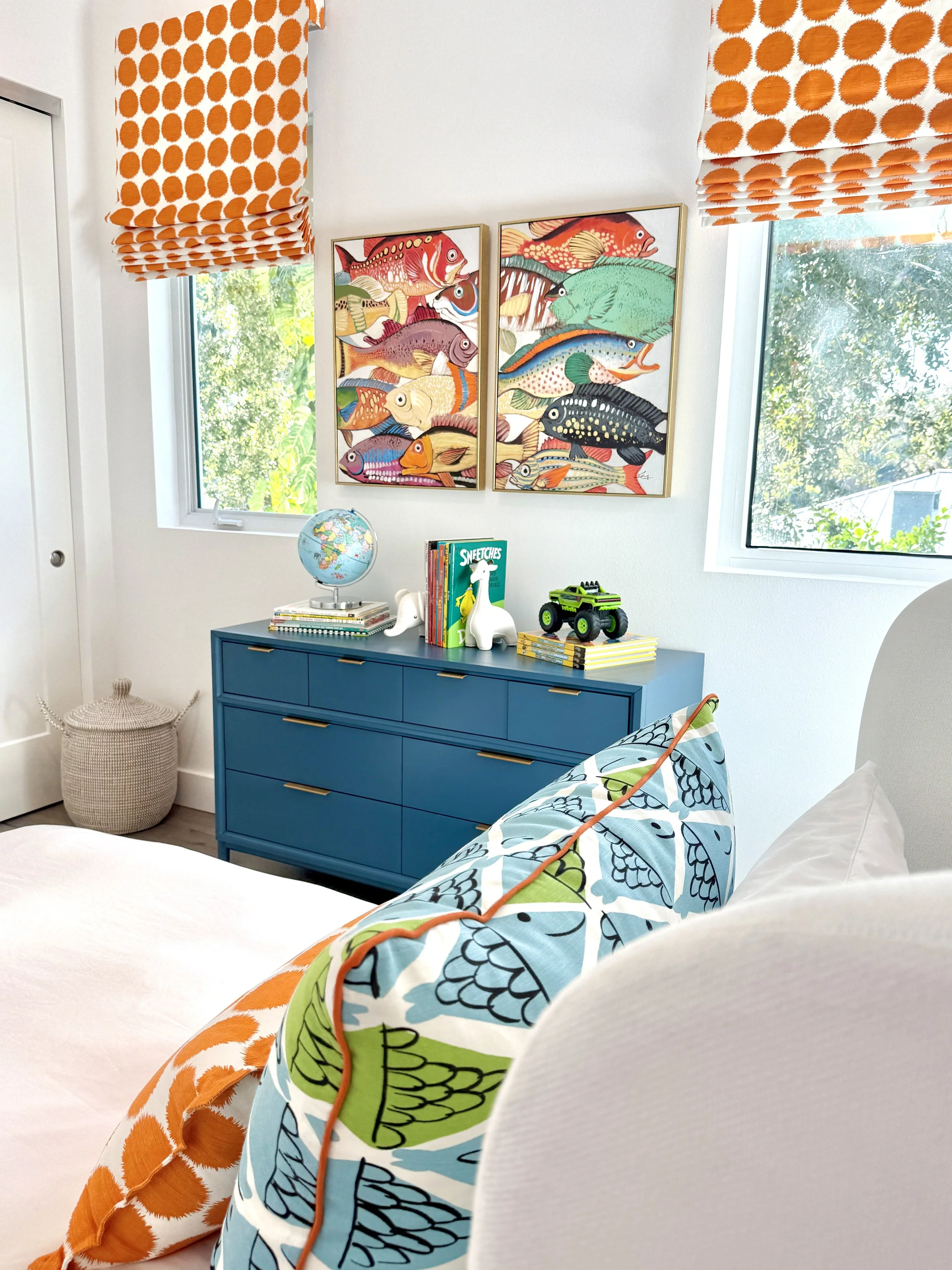 Child's bedroom in fish theme, featuring modern orange dot Schumacher roman shades and blue dresser.