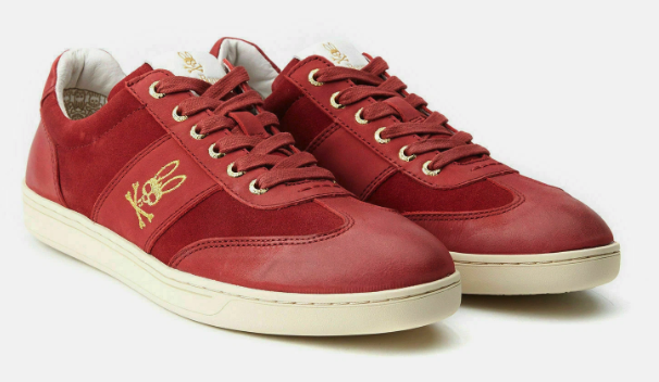 Red sneakers with gold embroidery of a rabbit and a skateboard, white soles, lace-up design.