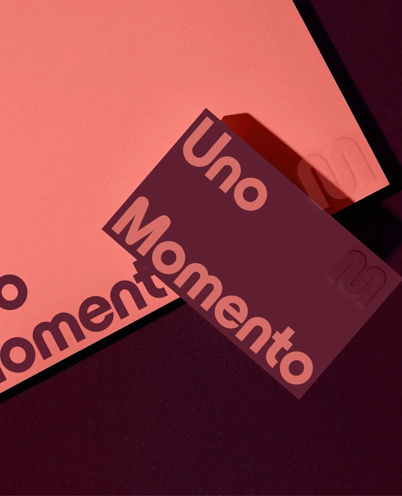 A pink board with a sticker that reads 'UON Momentto' partially peeled off, revealing a black background.