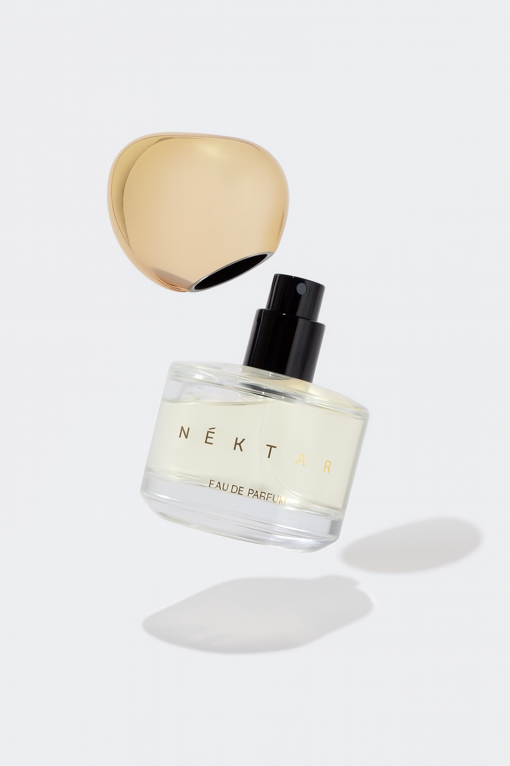 A perfume bottle labeled 'NÉKTÁR Eau de Parfum' with a gold-colored cap floating in mid-air.