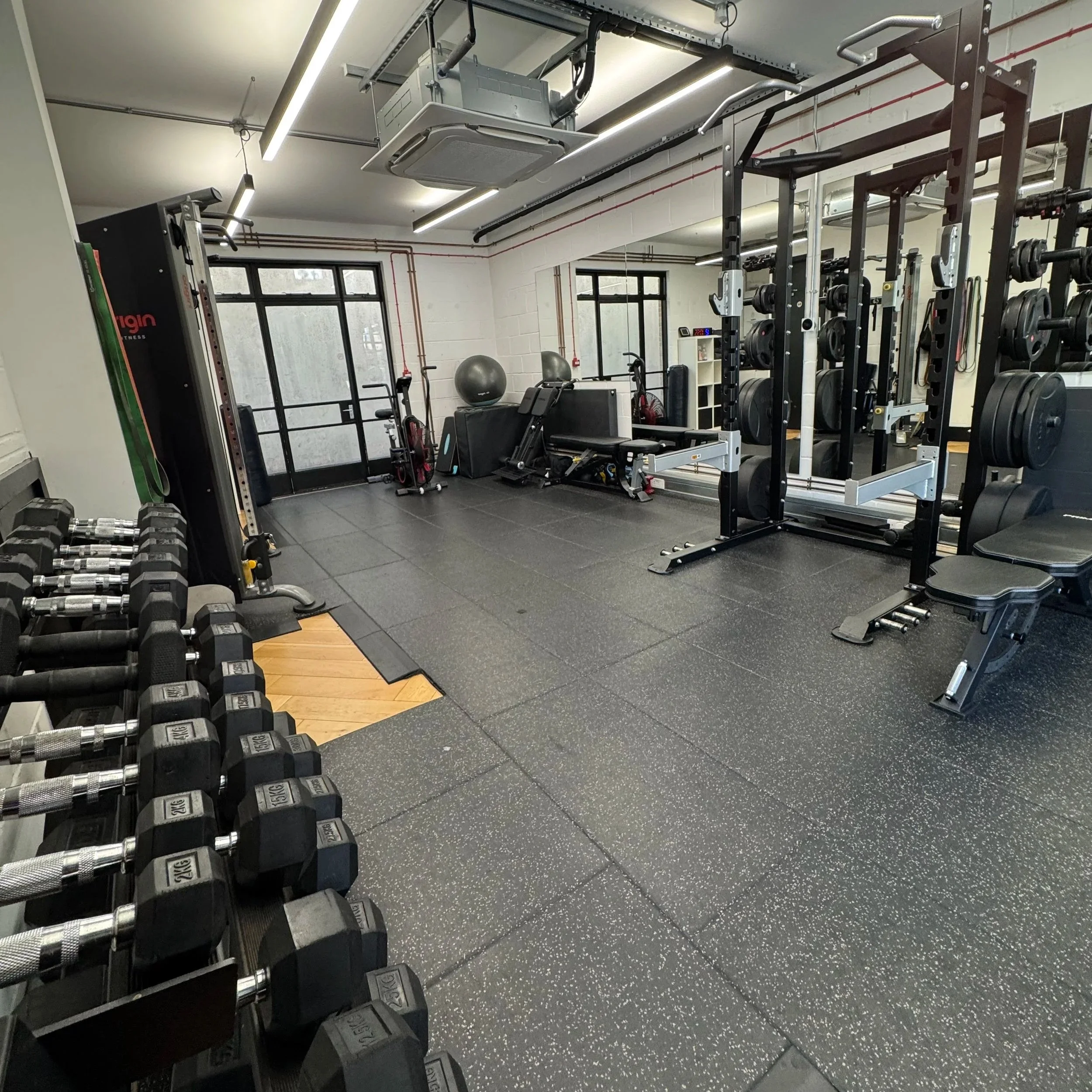 Private gym in Islington with squat rack, dumbbells, benches and open training floor at Oryan Fitness.
