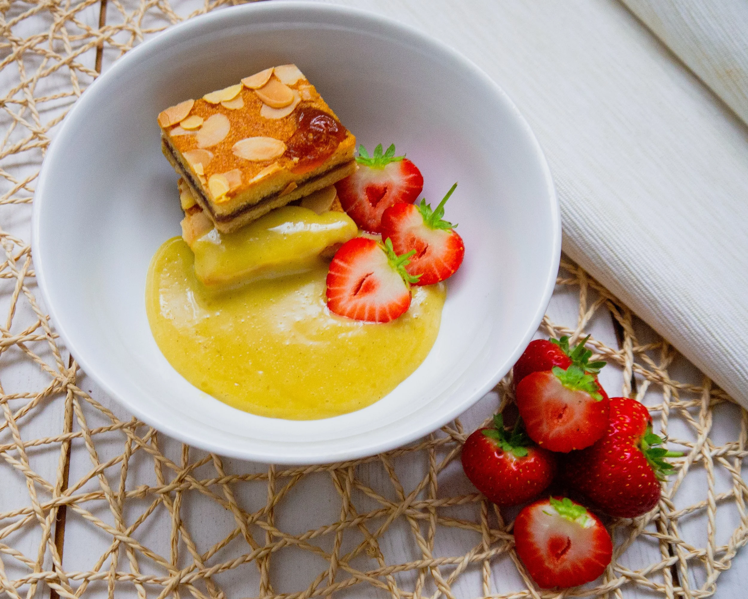 Bowl of dessert with coconut custard on the side and strawberries all in a white bowl