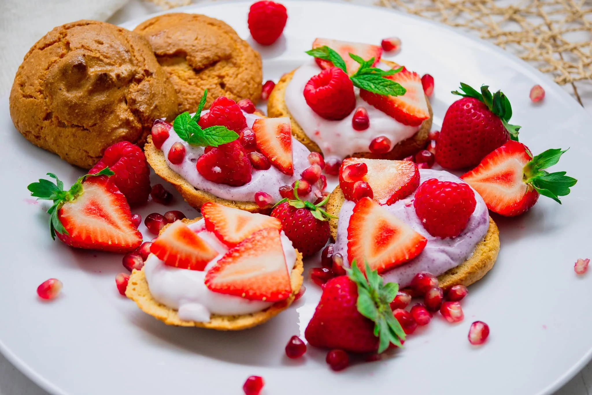 A white plate with sugar free scones topped with yoghurt and berries garnished with mint