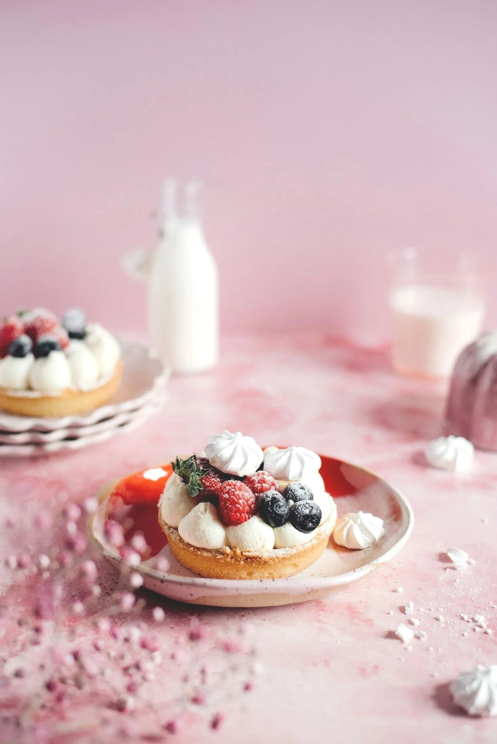 a fruit tart on a pink plate with mini meringue's