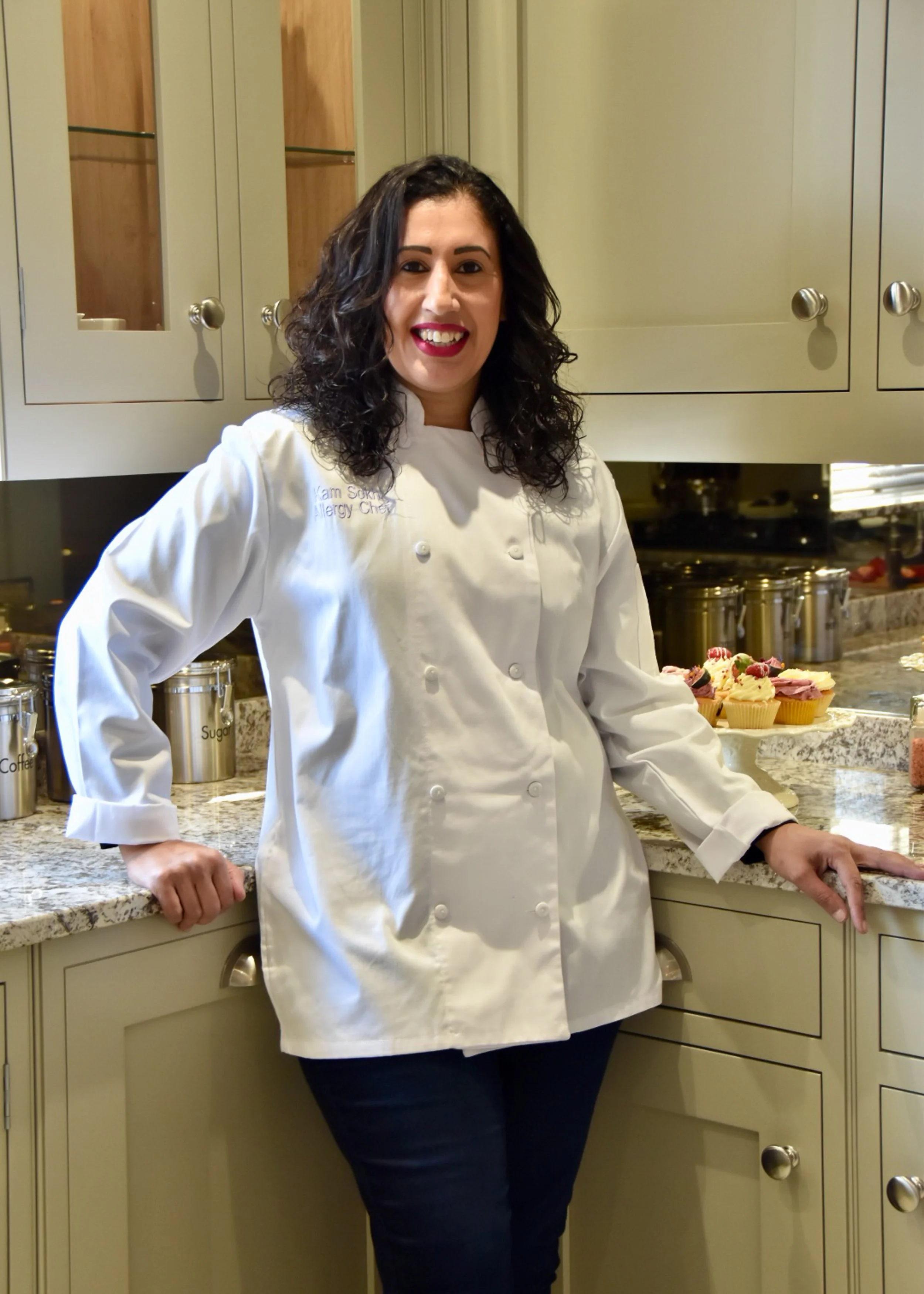 Kam wearing a white shirt stands in a kitchen, opening a glass oven