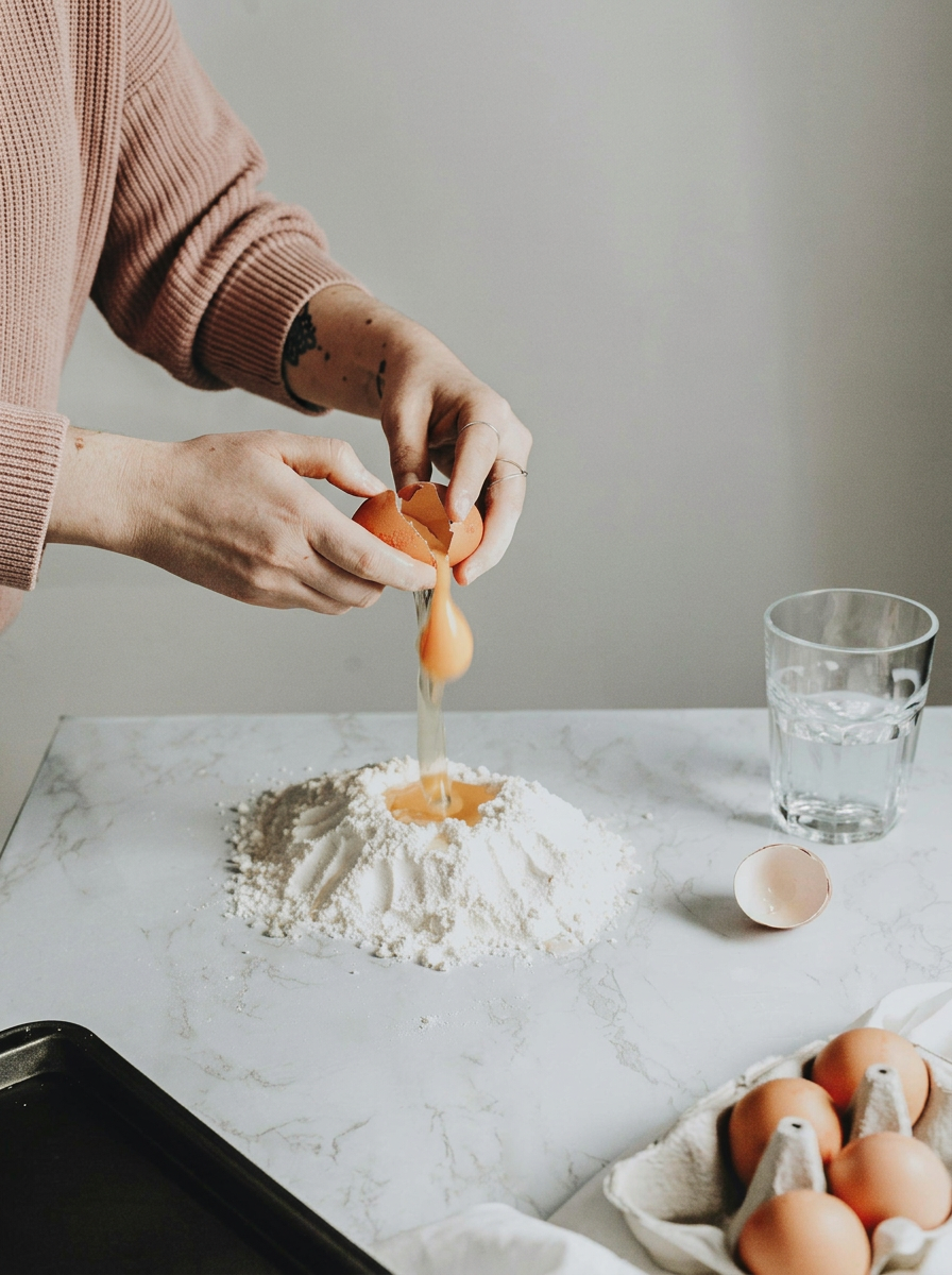 a lady cracking an egg into flour